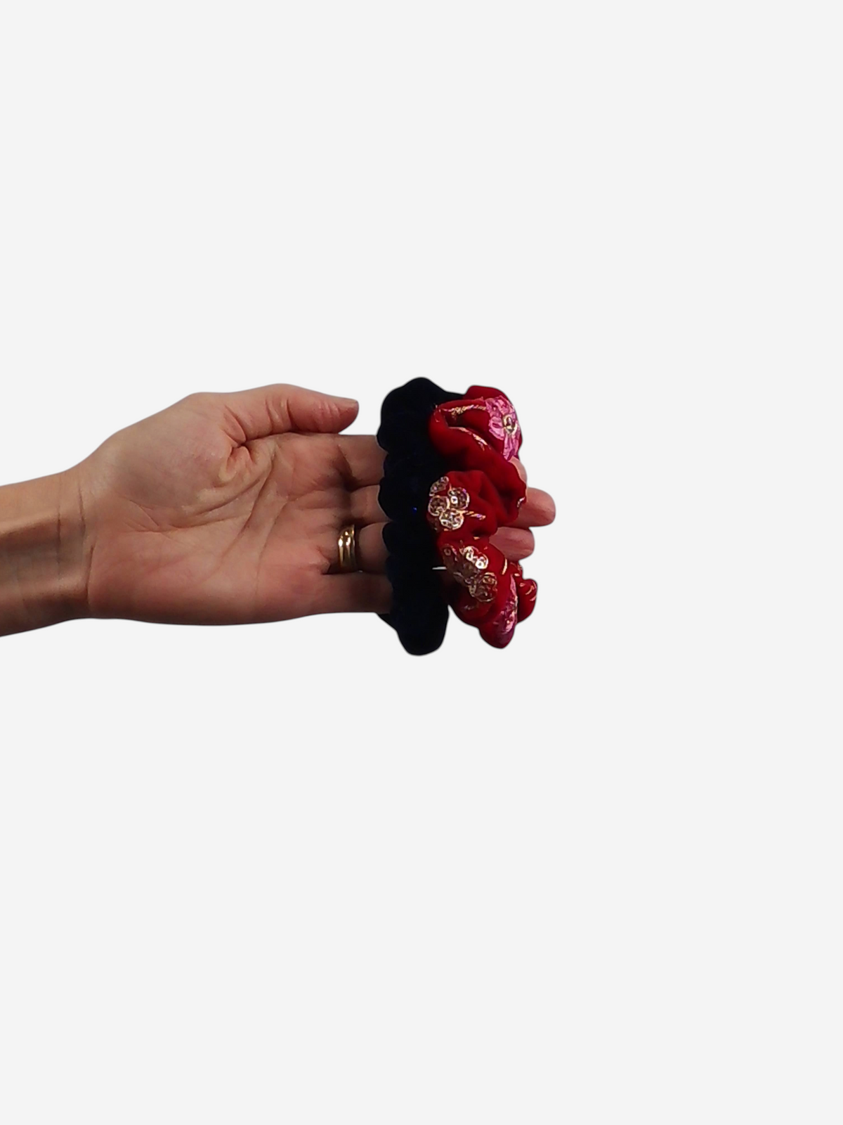 She Lives Beauty handmade velvet scrunchie in black and red with floral embroidery held in a hand
