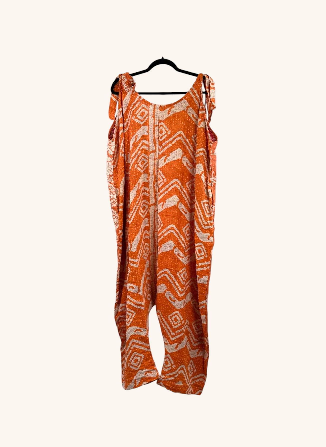 She Lives Beauty orange and white vintage kantha cotton harem jumpsuit with geometric patterns hanging on a hanger