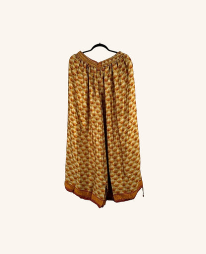 She Lives Beauty vintage rasgulla silk wide leg pants in a warm orange and yellow floral print on a hanger.